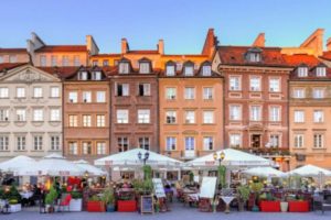Häuserreihe mit Sitzmöglichkeiten und Sonnenschirmen davor